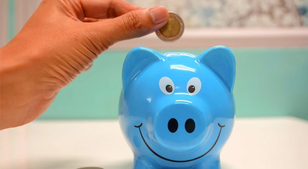 Picture of a person putting money into a piggy bank